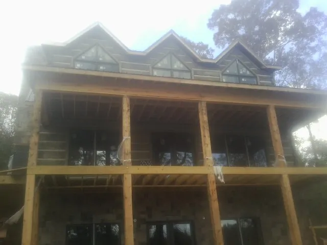 Dormers and porch framing on a large log home under construction — Roof Coating work by our crew in Uniondale