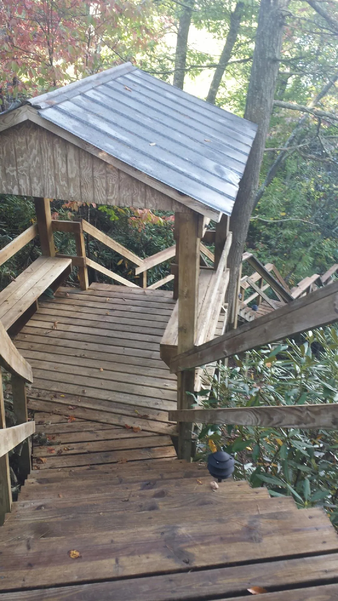 Metal roofed shelter over wooden steps on a wooded walkway — Skylight Repair & Installation work by our crew in Uniondale